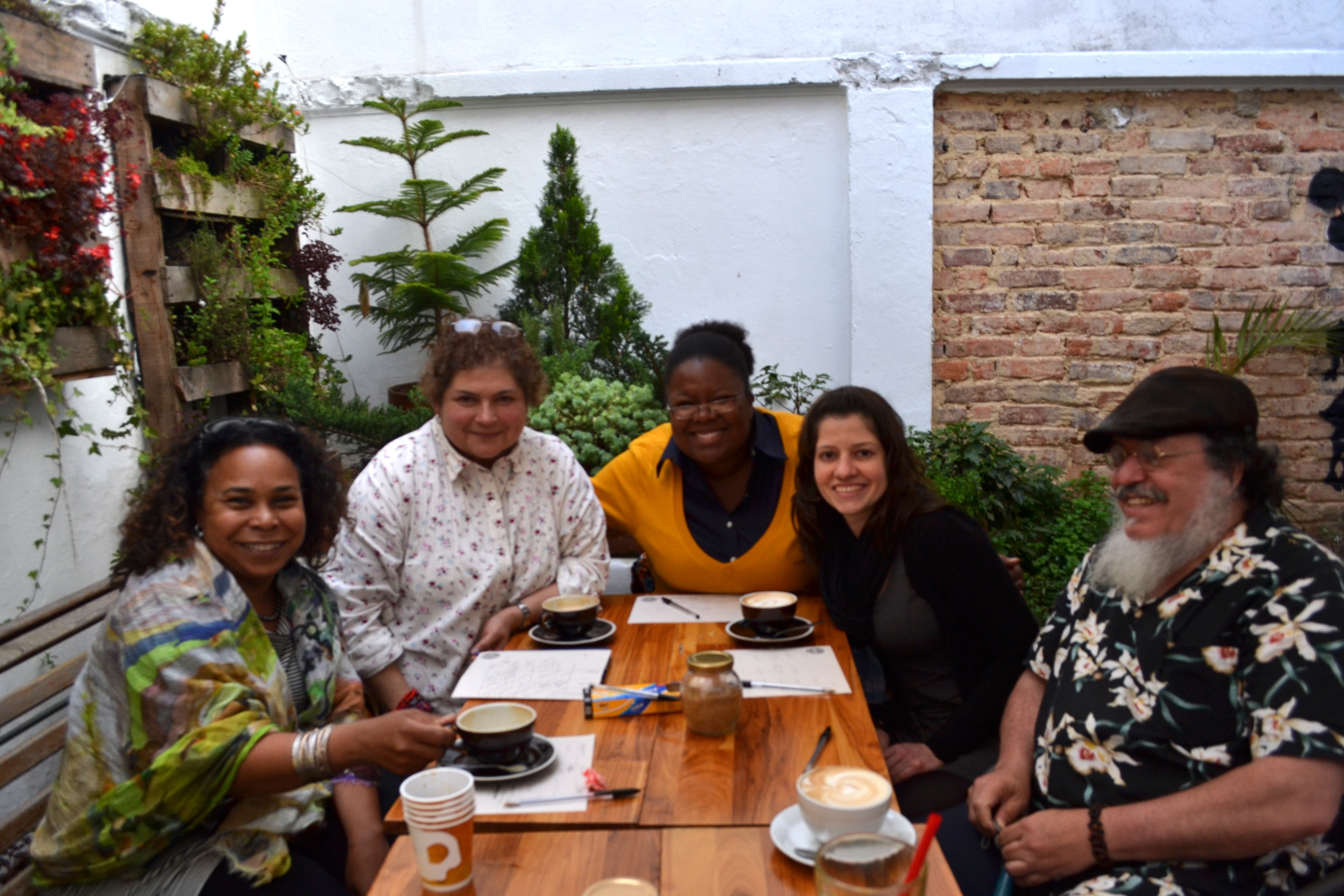 5 Fulbright Scholars pose with coffee around a table 