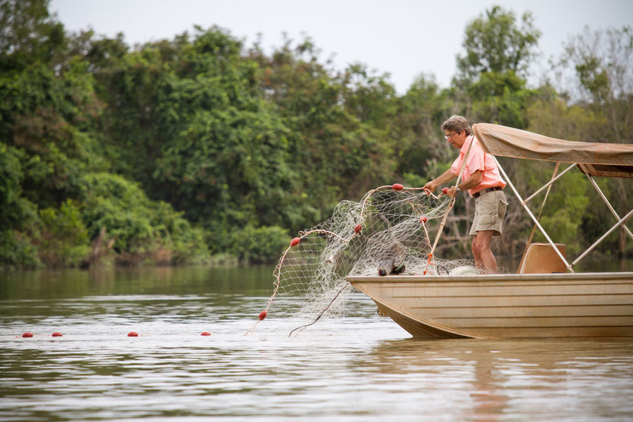 Tim Berra casts a net off a small fishing boat