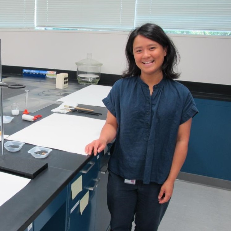 A woman standing at a lab counter smiling