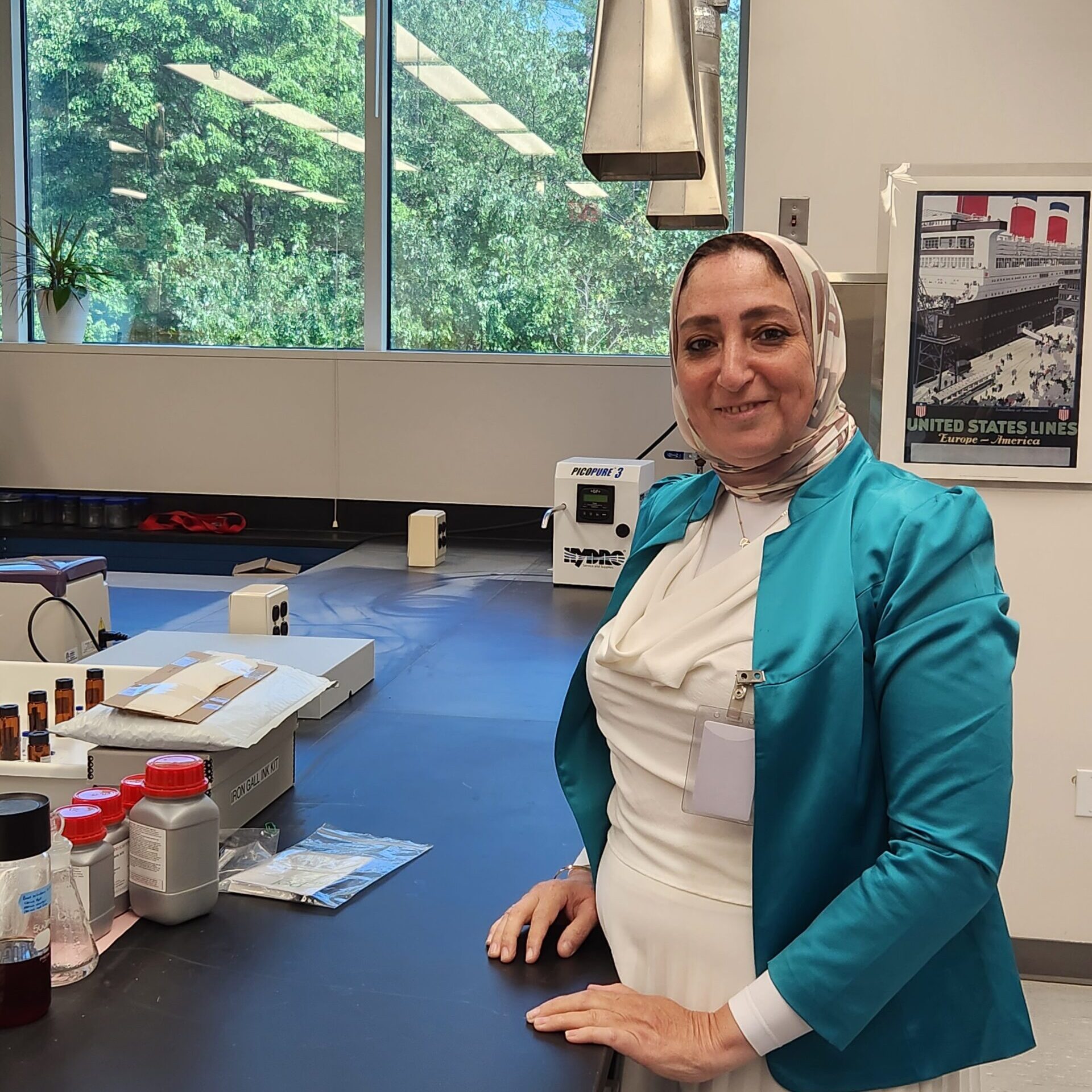 A woman standing at a lab counter smiling