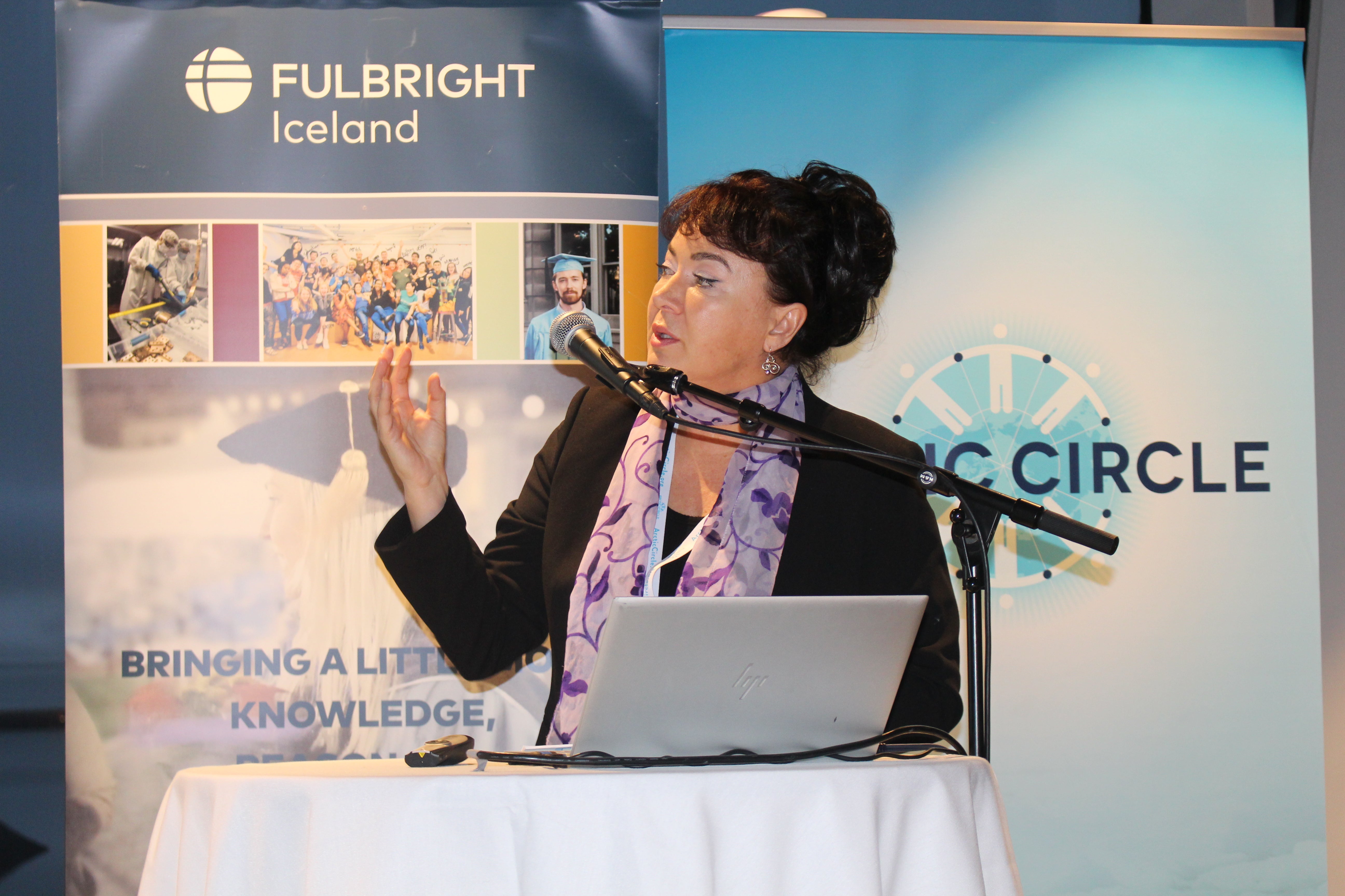 A woman speaks at a lectern with Fulbright Iceland and Arctic Circle banners behind her.
