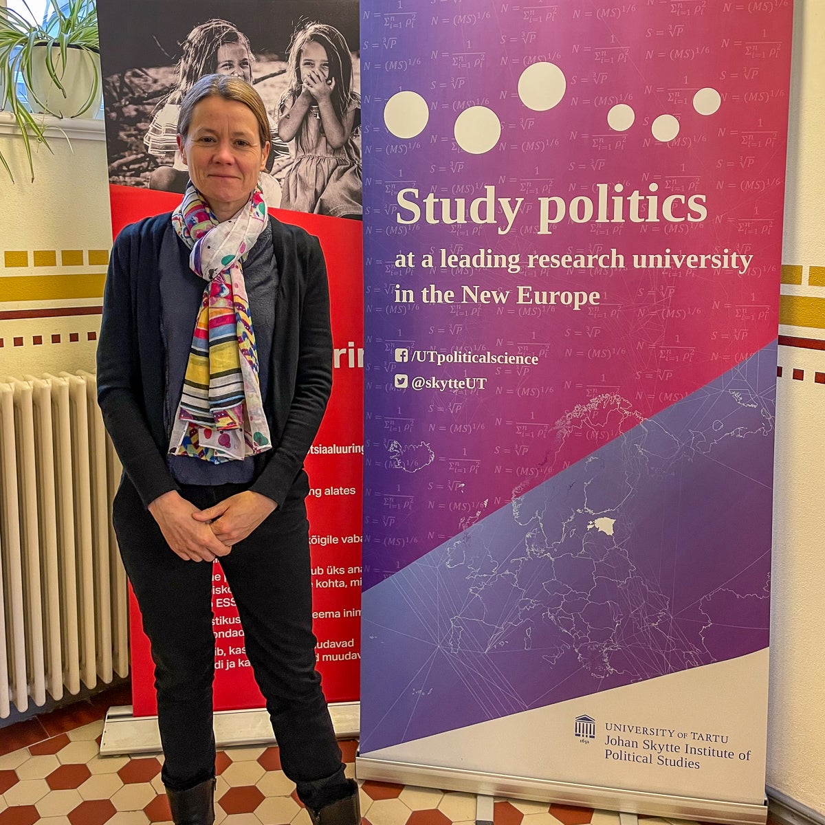 Person standing in front of red and purple promotional banners indoors.