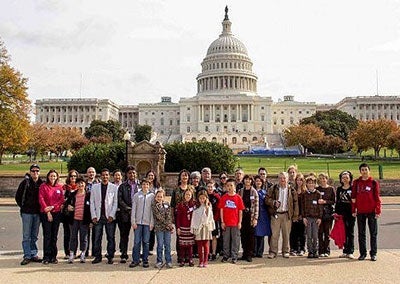 A group of people are gathered in front of the U.S. Capitol building on a cloudy day.